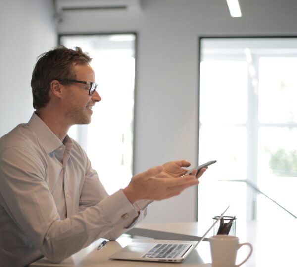 Confident businessman engaging in a discussion with a smartphone in a contemporary office setting.