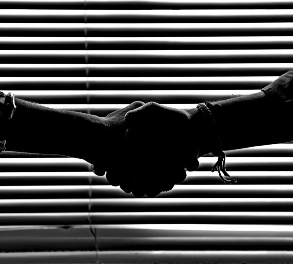 Silhouette of two people shaking hands symbolizing partnership and trust.